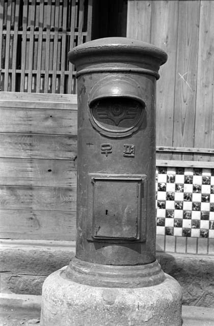 Tall metal structure on sidewalk, possibly a mailbox.