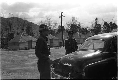 Military personnel beside a car