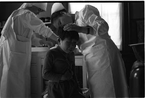 Child crying as nurse cuts hair