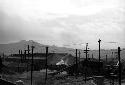 Shot of warehouse area, many electrical wire poles; mountain in background.