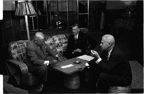 Three men sitting around a table in a lounge