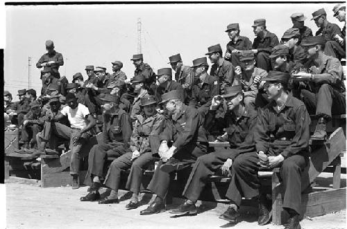 Men in military uniform sitting on a bleacher