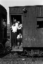 Three men standing in the doorway of a wooden train car.