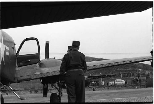 Two men standing near the wing of a plane