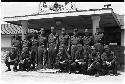 Group of men in uniform posing for picture in front of a building