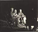 Lorna Marshall, John Marshall, and Laurence Marshall sitting by a fire (print is a cropped image)