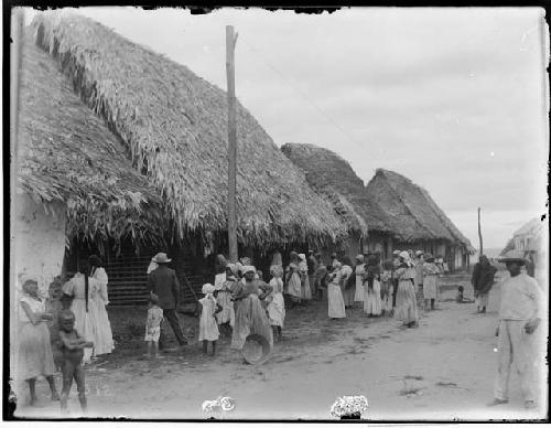 People on road, in front of rural huts
