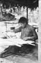 Woman weaving on loom in hut