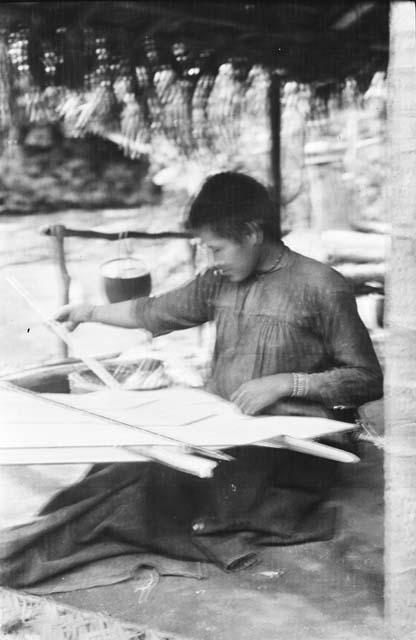 Woman weaving on loom in hut