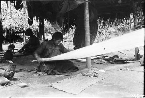 Woman weaving on loom in hut