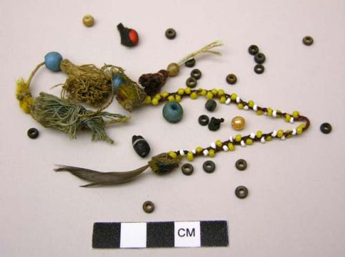 Carton box of beads, fiber, a feather, and a part of beaded ornament