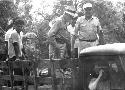 Gordon Willey (In white cap) and others standing in back of truck, Mrs Willey (?