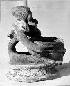 Pot 17, Grave 2. Pottery figure seated on low platform holding a small bowl