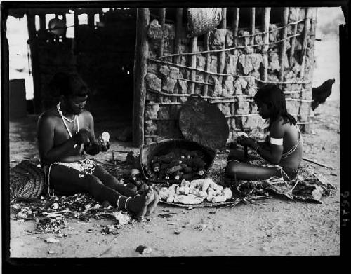 Girls scraping skins off cassava bulbs