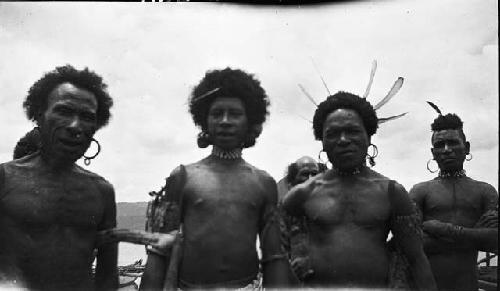 Men wearing costumes feathers, nose rings, earrings and boats