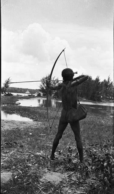 Rear view of man shooting a bow and arrow