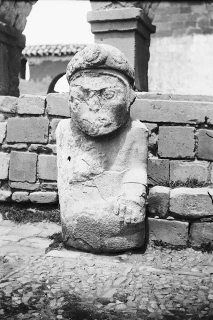 Stone anthropomorphic sculpture in front of unknown structure