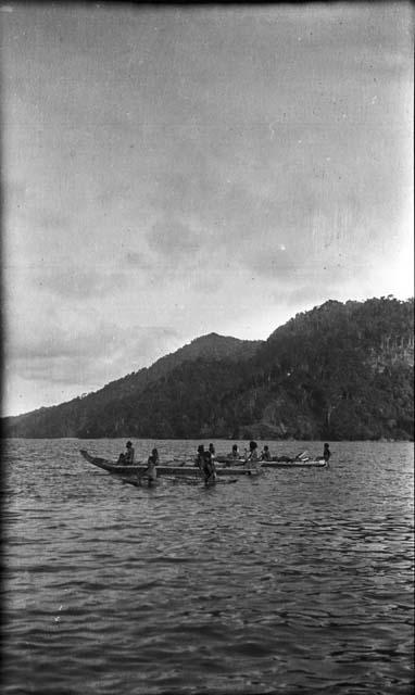 Men rowing double outrigger dugout canoes