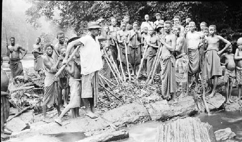 Group gathered near stream crushing plant materials with sticks