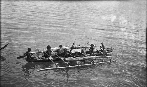 Men rowing double outrigger dugout canoe