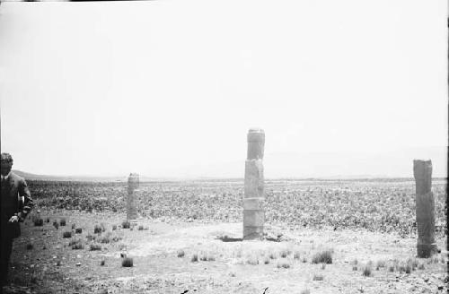 Man standing near three tall stone, anthropomorphic sculptures