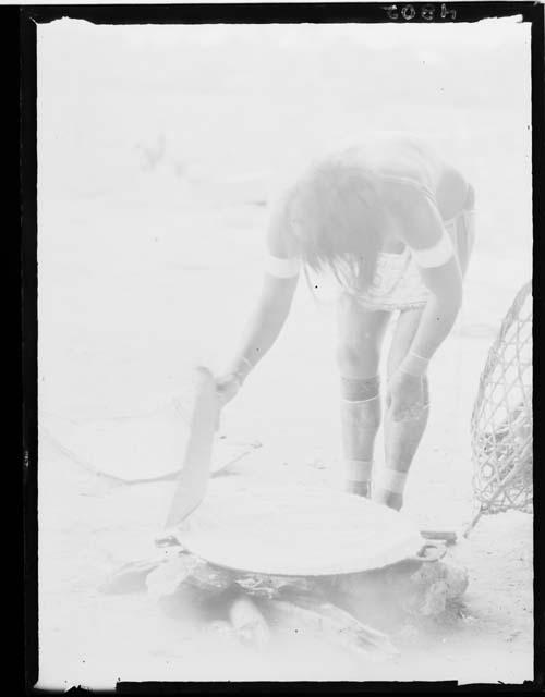 Girl making cassava bread - in the act of patting cassava