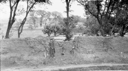 Children standing by wall and trees