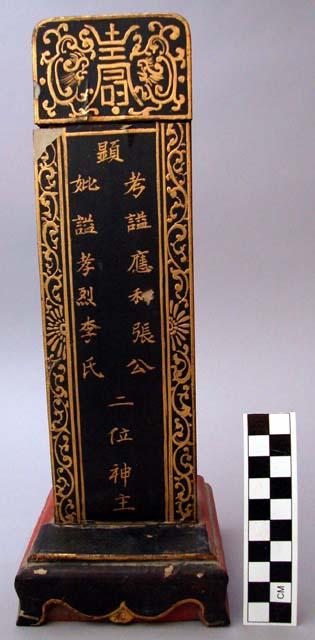 Ancestral tablet of wood covered with black, gold, and red paint