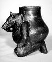 Ceramic effigy jar, zoomorph kneeling and holding snout, dark slip