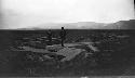 Man and woman standing on large, shaped monoliths in valley