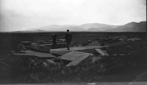 Man and woman standing on large, shaped monoliths in valley