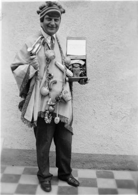 Man dressed in traditional clothing, holding objects