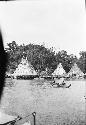 People in canoes in front of homes along river