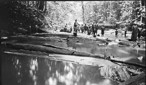 Group gathered near stream awaiting fish