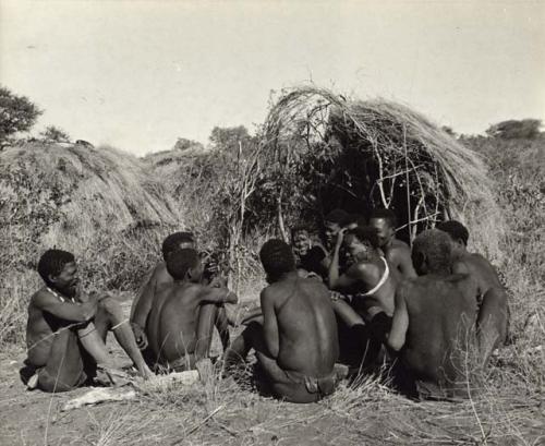 Group of people sitting in front of a skerm, telling stories, including Zuma (daughter of "Old Xama," wife of Gao), Xama, Gao (son of Debe, headman of Band 24 in Cho/ana) and /Qui (brother of "Gao Helmet") (print is a cropped image)