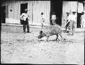 Men with pig in front of barn