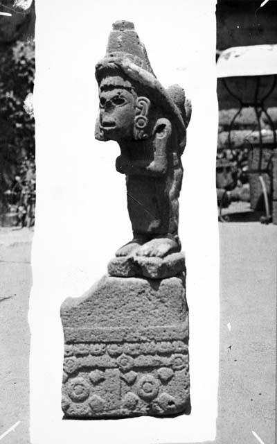 Statue of deity with strap headband holding ears of corn