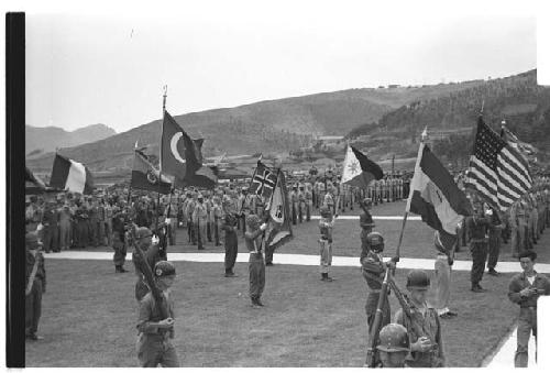 Soldiers in ceremonial formation, holding flags of their respective nations