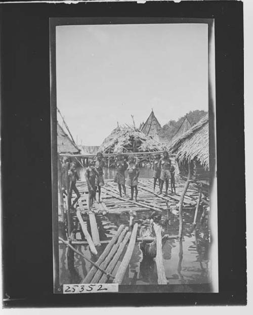 Group of women with tools in front of huts