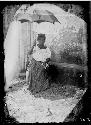 Woman sitting, holding an umbrella