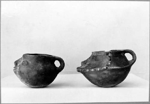 2 shoe-shaped vessels with faces, redish brown