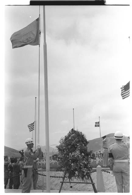 Soldier raising U.N. flag alongside wreath