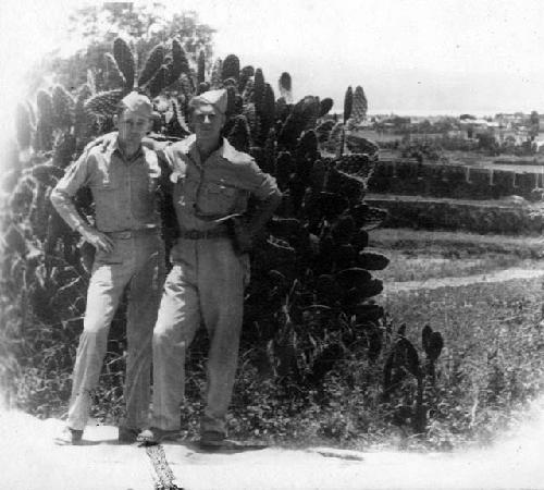 Two men standing in front of a cactus