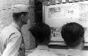 Man and boys reading a sign posted on a wall