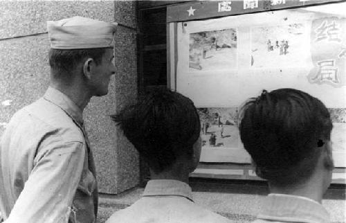 Man and boys reading a sign posted on a wall