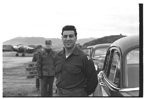 American soldier posing next to vehicles