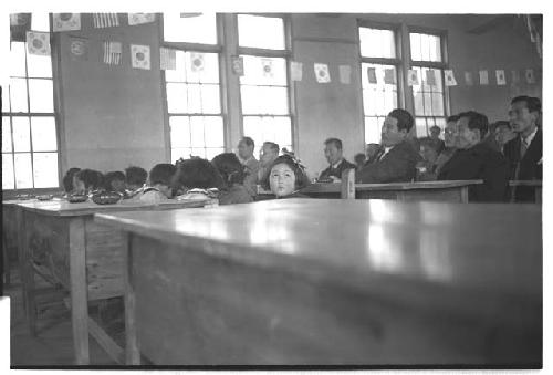 Several people in a room; focus on little girl looking up