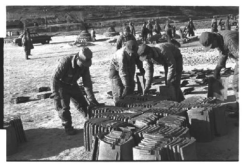 Men picking up unknown building material