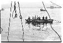 Men on a small boat heading to help a sinking U.S. Army tugboat