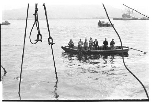 Men on a small boat heading to help a sinking U.S. Army tugboat